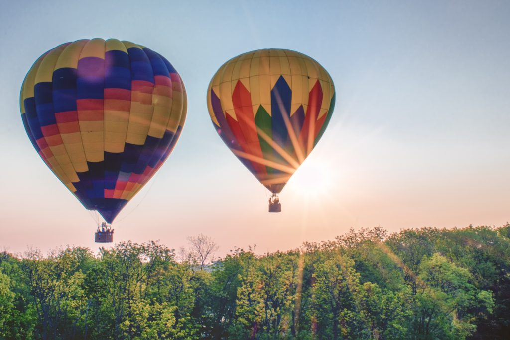 Two hot air balloons ascend over a treeline in Chester County, PA