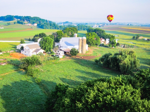 A Lancaster Hot Air Balloon floating over an Amish farm in Lancaster County, PA.